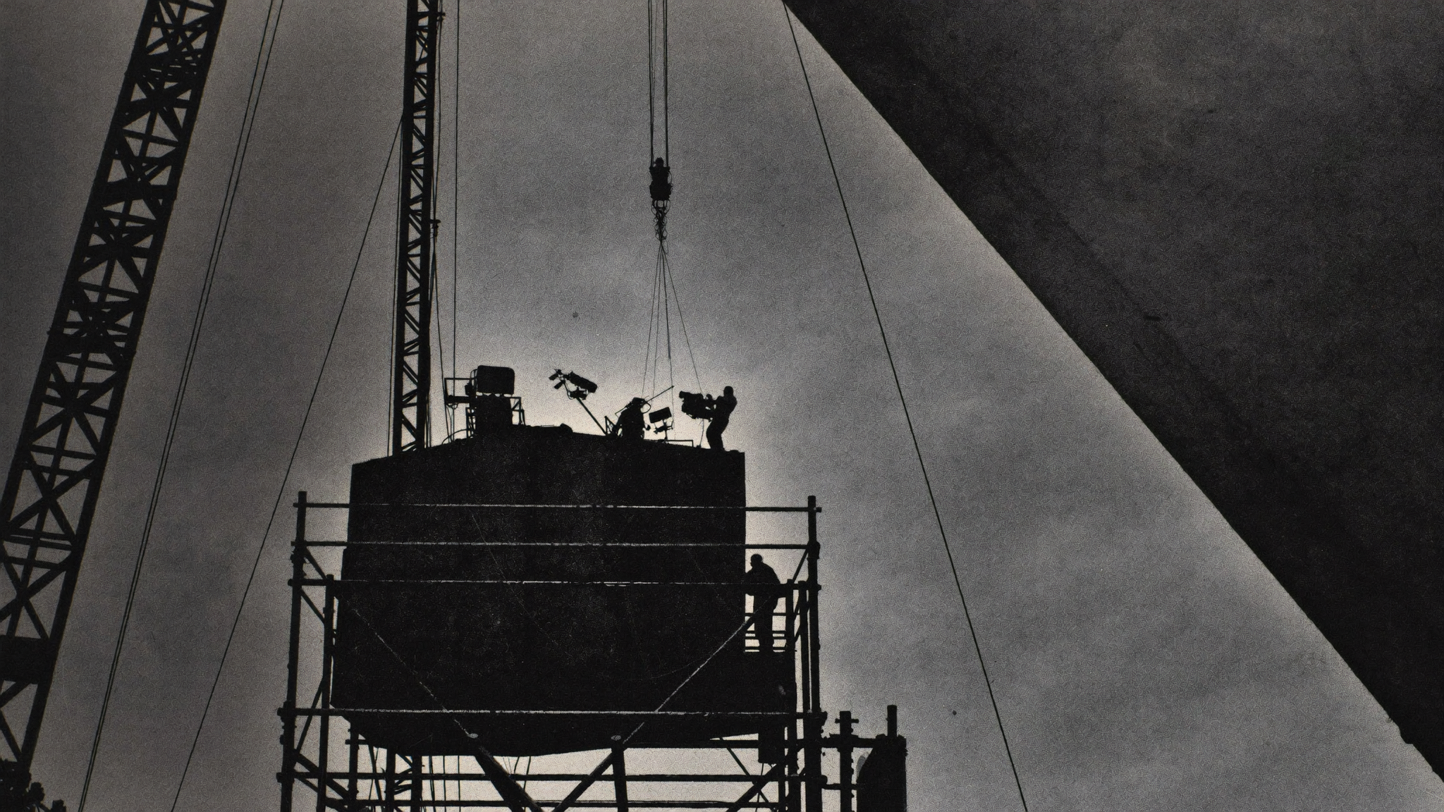A film crew building on industrial scaffolding against an open sky